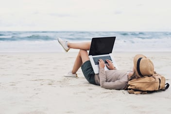 women on the beach working on laptop