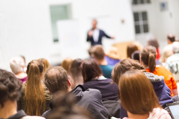 Dynamic speaker captivating and inspiring a large audience at a transformative coaching conference.